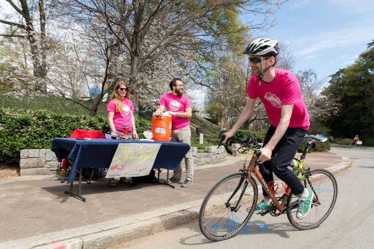 Bicyclist wearing pink with volunteers in Scicyle