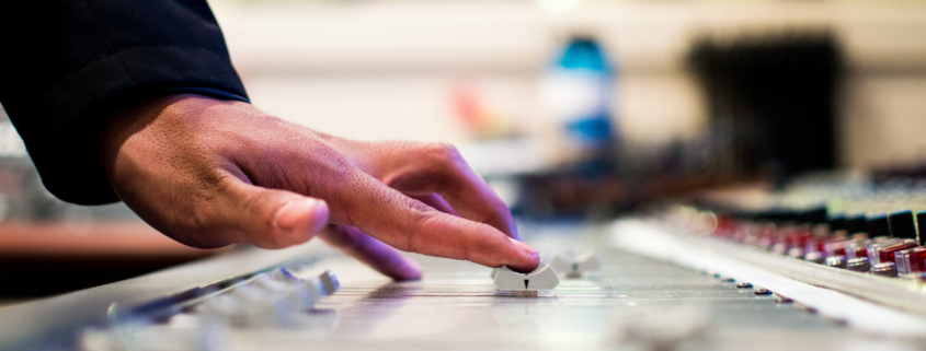 Close-up photo of a hand adjusting dials on a music mixer