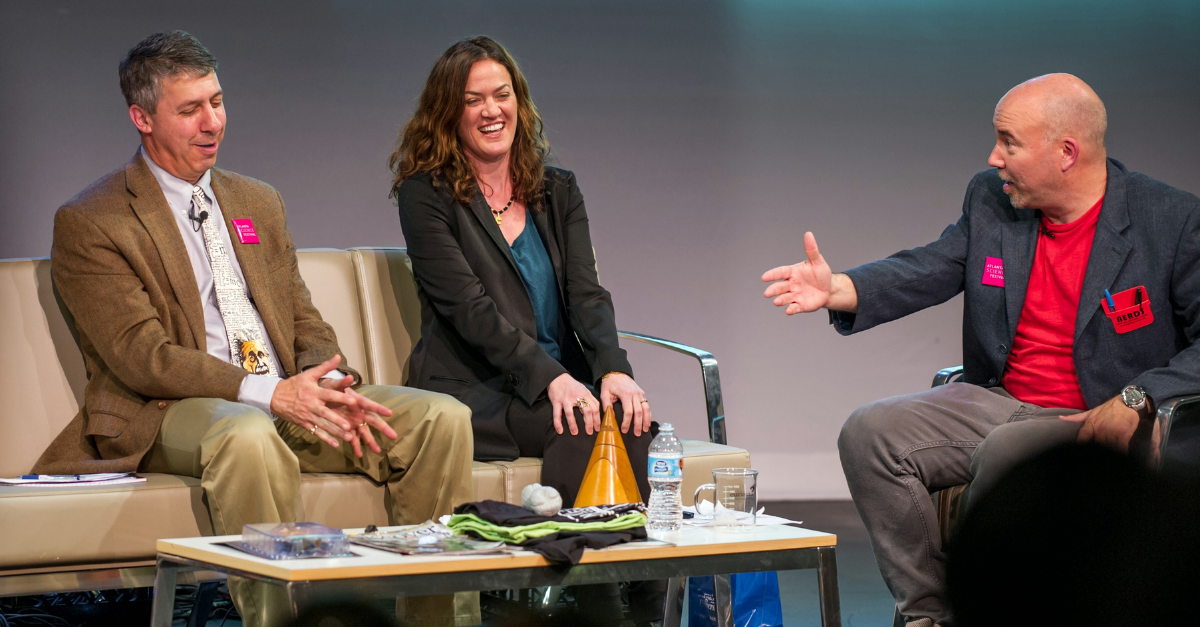 Three people laughing and having a conversation on stage