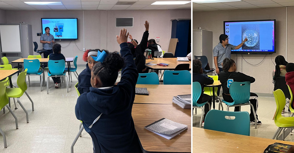 A 7th grader in a class raising their hand as Misael Romero-Reyes presents. 