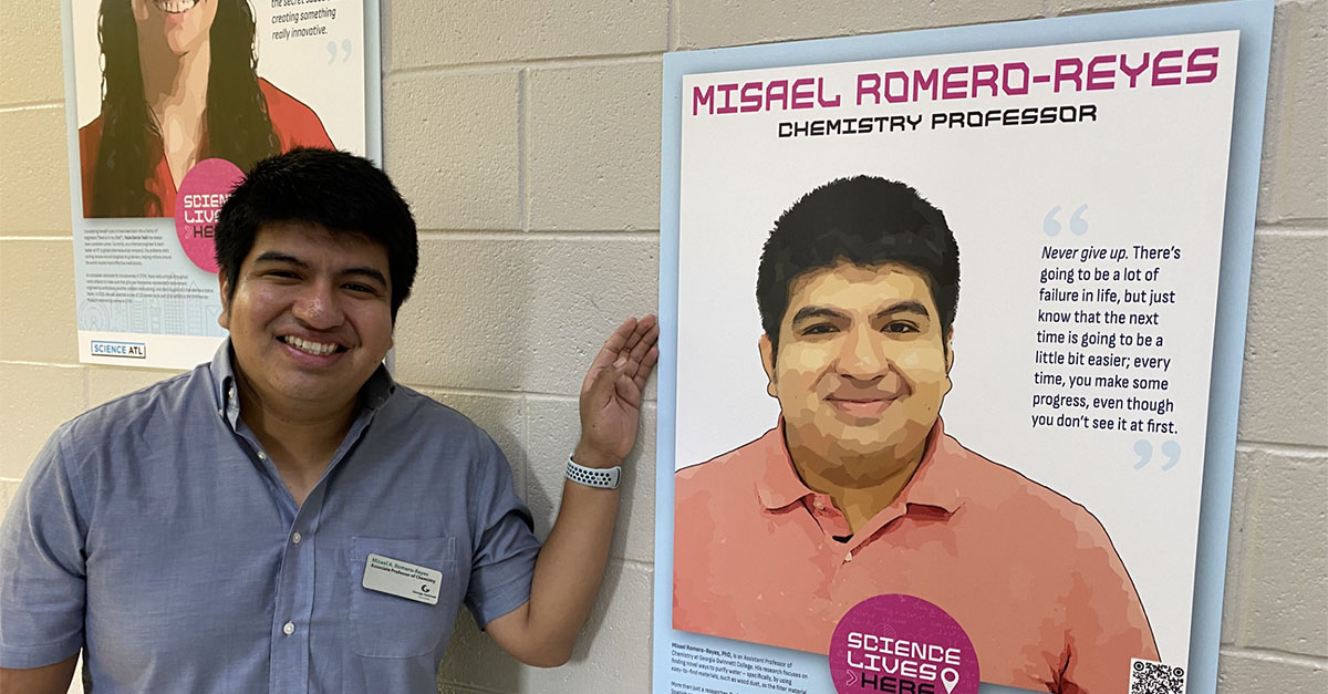 Misael Romero-Reyes standing in front of a poster about himself as a scientist.