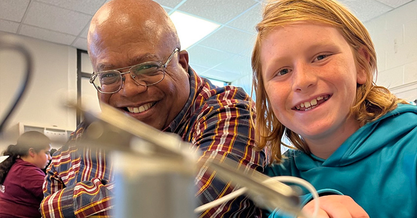 A STEM teacher smiling with student.