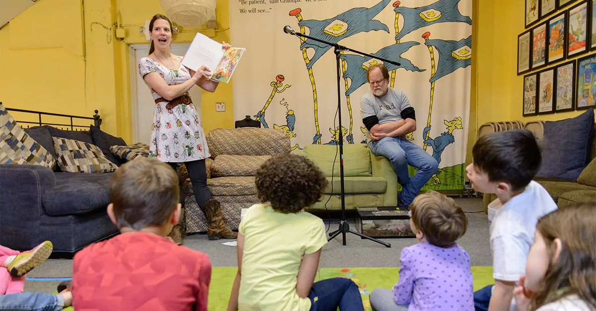A couple reading children’s books in a classroom.