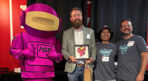 Alex Grizzell_award Man holding award next to an astronaut mascot